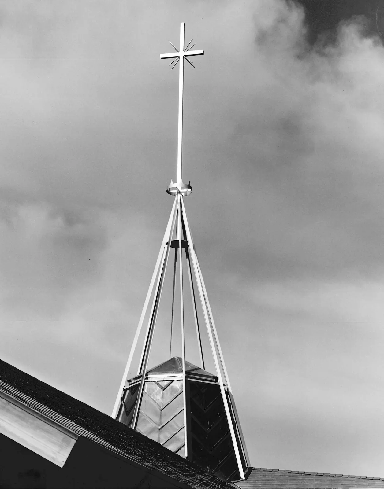 Close-up of the octagonal copper cupola, the open aluminum fleche, and the cross crowning St. Raymond.
