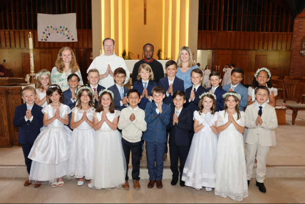 First Communion class gathered at the altar with clergy and catechists.